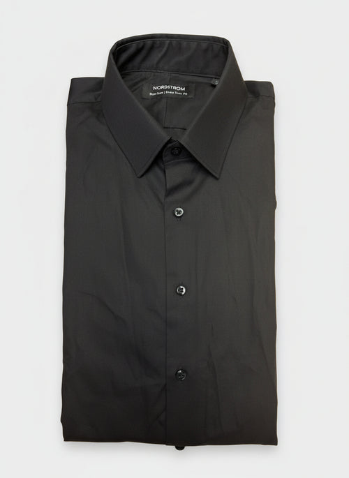 Folded black shirt with a label on a wooden surface